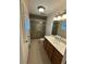 Bright bathroom featuring modern fixtures, a glass shower, and wood vanity with double sinks and stone flooring at 2062 Valiant Ne Dr, Atlanta, GA 30345
