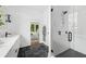 Bright bathroom with glass shower, black hexagon tile floors, and modern white vanity at 23 Walthall Ne St, Atlanta, GA 30317