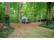 A serene backyard featuring a charming shed, lush greenery, and towering trees at 3788 Westwick Nw Ct, Kennesaw, GA 30152