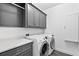 Efficient laundry room with modern washer and dryer, gray cabinets, and a countertop for folding at 6470 Long Island Nw Dr, Atlanta, GA 30328