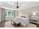 Bright main bedroom featuring a tray ceiling, a chandelier, neutral walls, light drapes, and wood floors at 6470 Long Island Nw Dr, Atlanta, GA 30328