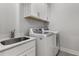 Functional laundry room featuring a sink, storage cabinets, and modern washer and dryer at 2125 Parkside Ln, Roswell, GA 30076