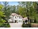 Elegant two-story home with a red tile roof, white exterior and lush landscaping in a wooded setting at 3401 Stillhouse Se Rd, Atlanta, GA 30339