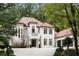 Elegant two-story home with a red tile roof, white exterior and lush landscaping at 3401 Stillhouse Se Rd, Atlanta, GA 30339