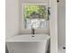 A bright bathroom features a freestanding tub next to a shower area with a large window that provides natural light at 2135 Huntington Dr, Loganville, GA 30052