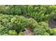 Aerial view of a house nestled among lush trees, featuring a pool, nearby pond, and what appears to be a tennis court at 10775 Shallowford Rd, Roswell, GA 30075