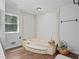 Bright bathroom featuring a tile tub with white pillars and a basket full of towels at 10775 Shallowford Rd, Roswell, GA 30075