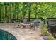 Stone fire pit and seating area surrounded by nature and a stone patio at 10775 Shallowford Rd, Roswell, GA 30075