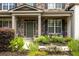 Inviting front porch with stone accents, a cozy seating area, and lush landscaping around the entrance at 374 Heritage, Woodstock, GA 30188