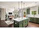 Open-concept kitchen and dining area with dark green cabinets, marble countertops, and stainless steel appliances at 374 Heritage, Woodstock, GA 30188