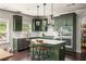 Kitchen features stylish green cabinets, stone countertops, stainless appliances and modern pendant lighting at 374 Heritage, Woodstock, GA 30188