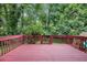 View of a painted back deck with a railing, a small gate, and a lush green forest in the background at 4345 Tucker North Dr, Tucker, GA 30084