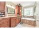 Beautiful bathroom with granite countertop, wood cabinets, tiled walls, and soaking tub under a window at 5028 Jamie Ne Ct, Woodstock, GA 30188