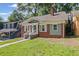 View of a charming home with brick and siding, framed by green trees and a front yard at 1585 Olympian Sw Cir, Atlanta, GA 30310