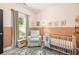 Inviting bedroom with pink walls, soft carpeting, a crib, and a comfortable rocking chair at 1296 Plaza Sw Ave, Atlanta, GA 30310