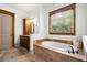 Elegant bathroom featuring a soaking tub, wood cabinets, and travertine tile flooring at 49 Waterside Se Dr, Cartersville, GA 30121