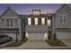 Exterior shot of modern townhomes displaying a well-manicured lawn, front-entry garages, and classic architectural details at sunset at 1247 Winterhaven Dr, Cumming, GA 30041