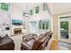 Spacious living room with a stone fireplace, built-in shelving, tall ceilings, and large windows overlooking a green backyard at 1285 Willow Park Way, Cumming, GA 30041