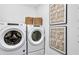 A modern laundry room with front-load washer and dryer, complemented by decorative art and woven baskets for storage at 4660 Rosarian Drive, Cumming, GA 30040
