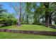 Large, tree-lined backyard featuring a retaining wall with a lush, green lawn at 1112 Evelyn Drive Dr, Forest Park, GA 30297