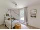 Bright bedroom with canopy bed frame, soft neutral colors, large window and woven ottoman at 4023 Anvil Block Rd, Ellenwood, GA 30294