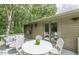 Relax on the patio with comfortable seating, a table, and views of the surrounding trees at 4023 Anvil Block Rd, Ellenwood, GA 30294