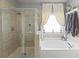 Bathroom featuring a glass enclosed shower, soaking tub and a large window with white curtains at 110 Ashbury Circle Cir, Dallas, GA 30157