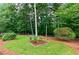 Landscaped backyard featuring a planted garden and wooded perimeter at 6490 Ivey Hill Dr, Cumming, GA 30040