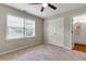 This carpeted bedroom has a ceiling fan and a door to a full bathroom with wooden floors and white cabinets at 5741 Stonekirk Walk Northwest, Acworth, GA 30101