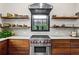 Kitchen featuring stainless steel stove, range hood, open wood shelving, and marble countertops at 261 Ormond Se St, Atlanta, GA 30315