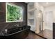 Stunning bathroom showcasing a modern black tub, a glass shower, and built in shelves at 3711 Mountain Cove Rd, Snellville, GA 30039