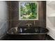 Elegant bathroom featuring a black standalone tub with sleek fixtures and black marble tiling at 3711 Mountain Cove Rd, Snellville, GA 30039