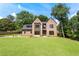 Stunning brick home showcasing modern design with large windows and a lush green lawn at 3711 Mountain Cove Rd, Snellville, GA 30039