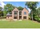 Beautiful brick home with modern accents, a well-kept lawn, and lush surrounding greenery at 3711 Mountain Cove Rd, Snellville, GA 30039