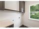 Well-lit laundry room boasts gray cabinetry and a window offering serene backyard views at 3711 Mountain Cove Rd, Snellville, GA 30039