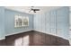 Bedroom with hardwood floors, light blue walls, custom paneling, and a large window at 6630 Club Valley Ct, Suwanee, GA 30024