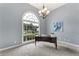Bright office space featuring a large window, modern desk, and elegant chandelier with soft, gray walls at 6630 Club Valley Ct, Suwanee, GA 30024