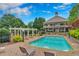 A stunning community pool surrounded by lounge chairs, a white pergola and lush landscaping at 6630 Club Valley Ct, Suwanee, GA 30024
