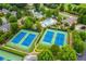 Aerial shot of well-maintained tennis courts and a pool, surrounded by trees and landscaping at 6630 Club Valley Ct, Suwanee, GA 30024