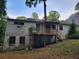 Back exterior of a weathered house with a wooden deck and a backyard overgrown with greenery at 1159 Eastridge Sw Rd, Atlanta, GA 30311