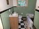 Bathroom with a pedestal sink, tub, green tile walls, and checkerboard floor, ready to be updated at 1159 Eastridge Sw Rd, Atlanta, GA 30311