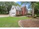 View of the two-story brick home with three car garage, sidewalk, and luscious yard at 1418 Mill Path Loop, Lawrenceville, GA 30045