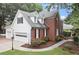 A two-story brick home with a three-car garage, manicured lawn and sidewalk at 1418 Mill Path Loop, Lawrenceville, GA 30045