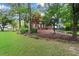 Manicured front yard with mature shade trees partially obscuring the brick home at 1418 Mill Path Loop, Lawrenceville, GA 30045