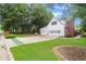 View of the 3 car garage with brick driveway and manicured lawn at 1418 Mill Path Loop, Lawrenceville, GA 30045