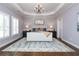 Elegant main bedroom with tray ceiling, decorative chandelier and a plush area rug at 1282 Kendrick Ne Rd, Brookhaven, GA 30319