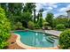 Stunning backyard pool featuring lush landscaping, stone pavers and two lounge chairs under an umbrella at 1282 Kendrick Ne Rd, Brookhaven, GA 30319