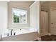 Corner bathtub with large window and shower featuring a white shower curtain at 6298 Gothards Ln, Douglasville, GA 30134