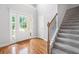 Bright foyer with hardwood floors, stairs with a carpet runner, and a glass-paneled front door at 9996 Village South Dr, Douglasville, GA 30135