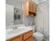 Well-lit bathroom featuring a wood vanity, toilet, and shower with printed curtain at 9634 Coastal Pointe Dr, Villa Rica, GA 30180